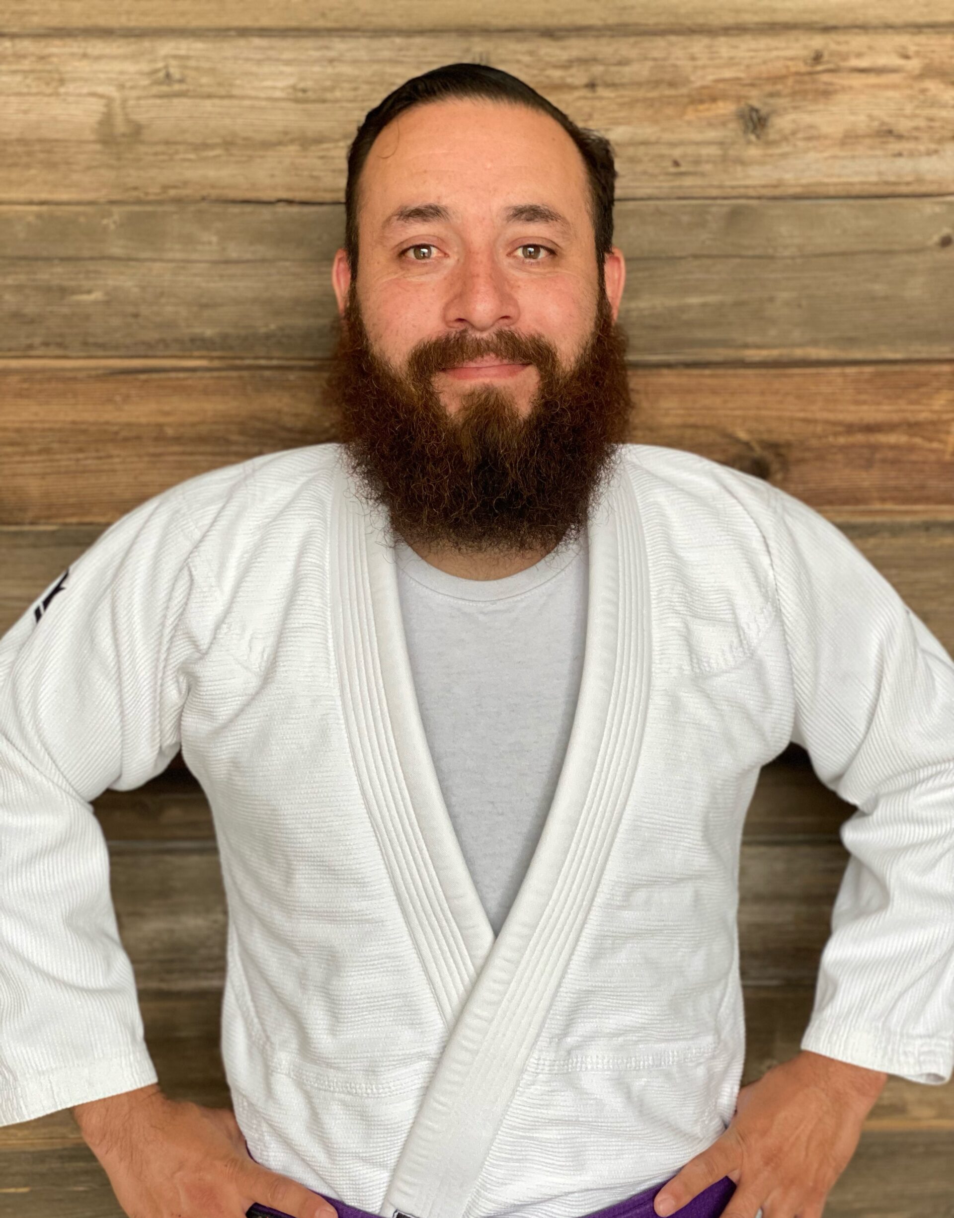 Coach Sal posing for a picture in a white Jiu-Jitsu gi with his black belt on in Blaine MN