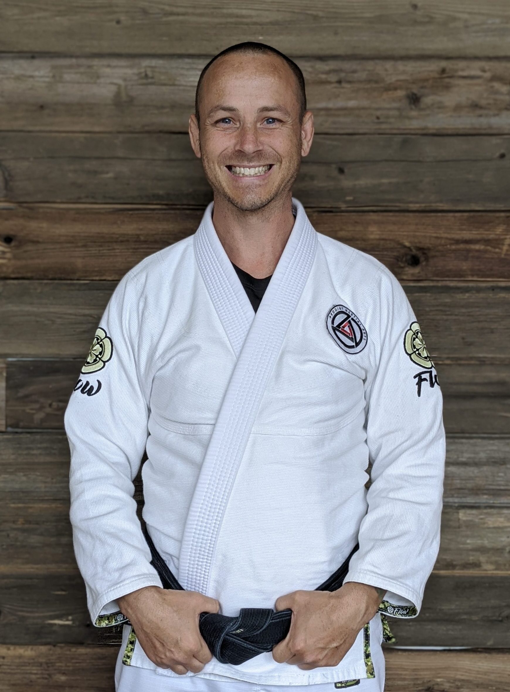 Professor Justin Kahmann posing for a picture in a white Jiu-Jitsu gi with his black belt on in Blaine MN