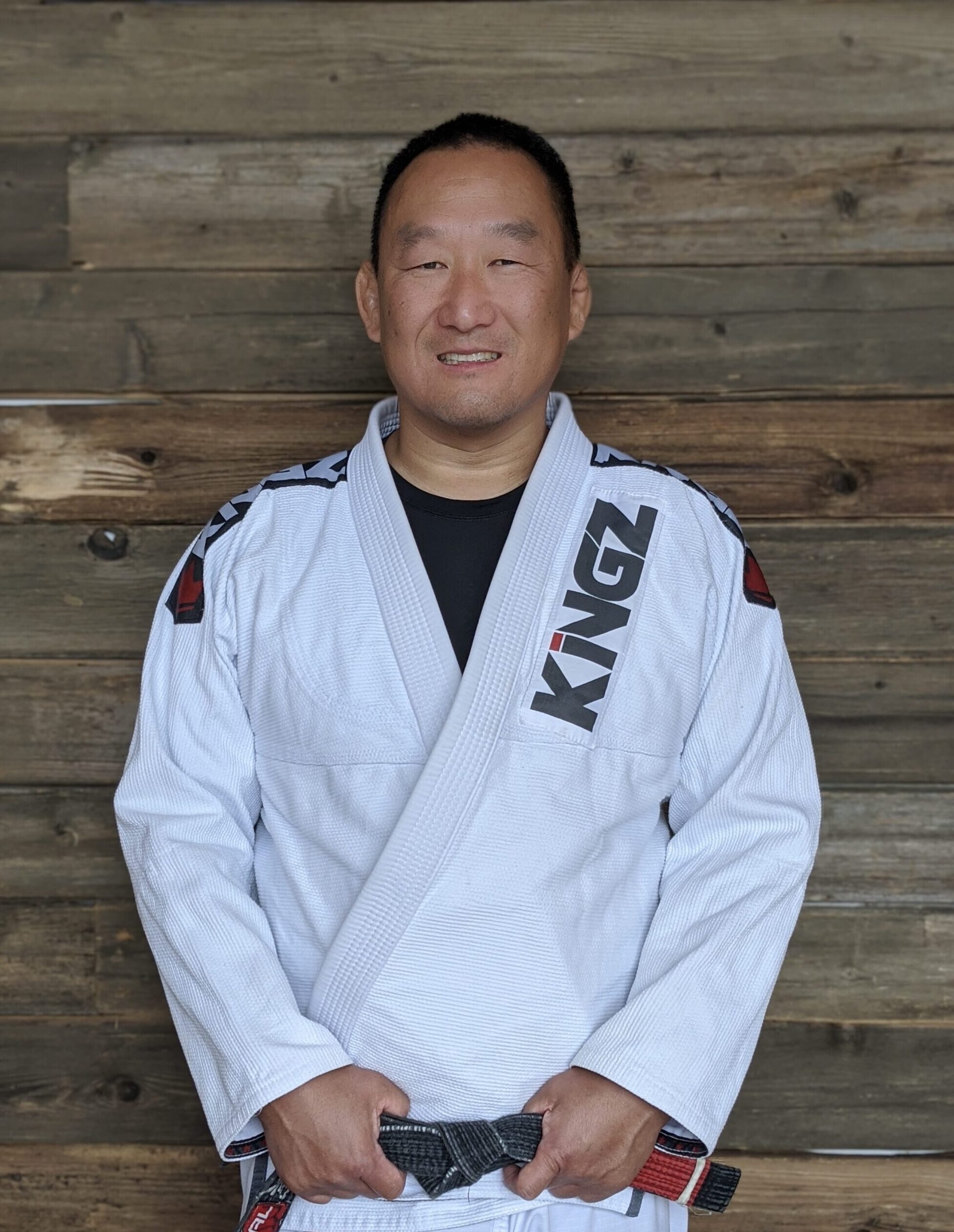 Professor Mike posing for a picture in a white Jiu-Jitsu gi with his black belt on in Blaine MN