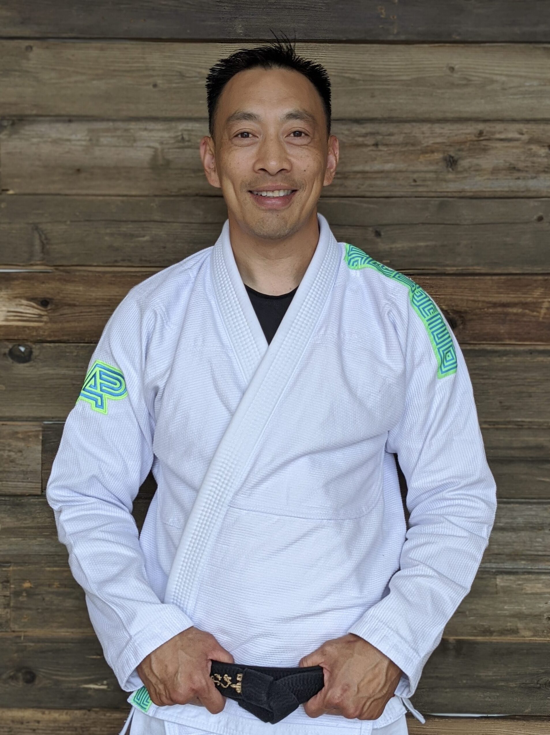 Professor Thao Le posing for a picture in a white Jiu-Jitsu gi with his black belt on in Blaine MN